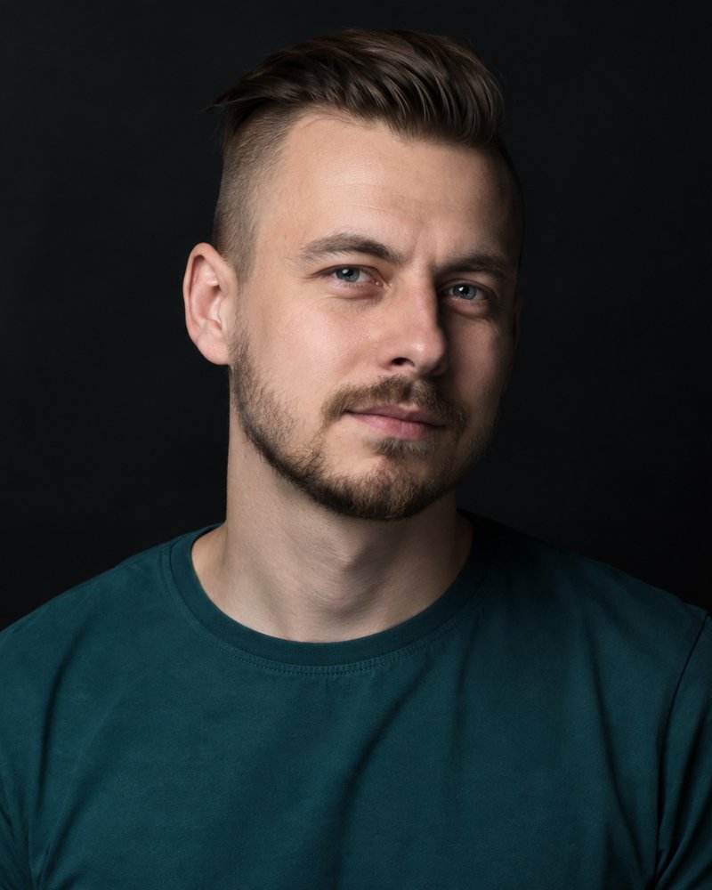 Mężczyzna około dwudziestu ośmiu lat, krótki bok, gładka koszulka, ciemne studio, bez napisu